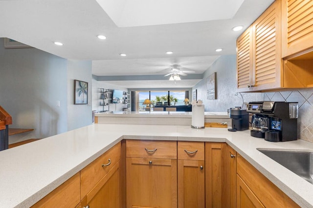 kitchen with backsplash, sink, kitchen peninsula, and ceiling fan