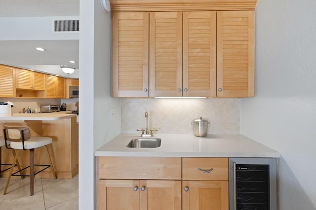 kitchen featuring wine cooler, sink, decorative backsplash, and light tile patterned floors