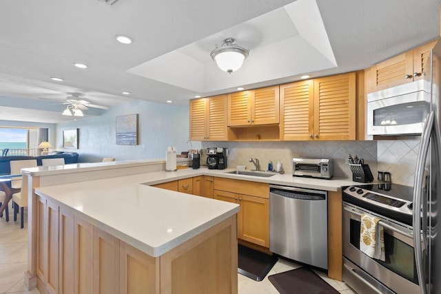 kitchen featuring sink, appliances with stainless steel finishes, tasteful backsplash, light brown cabinetry, and kitchen peninsula