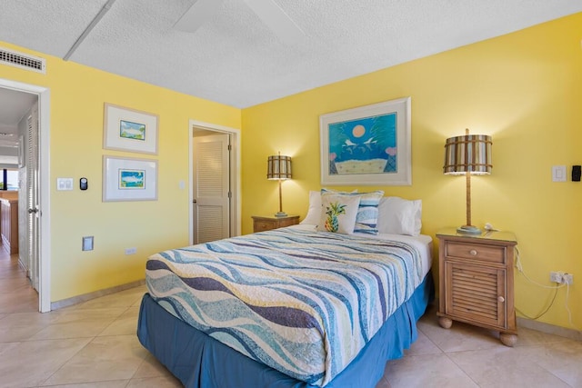 bedroom featuring ceiling fan, a textured ceiling, and light tile patterned flooring