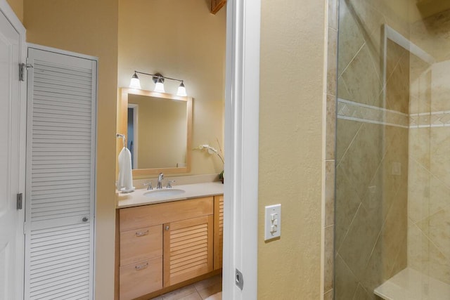 bathroom featuring a tile shower, vanity, and tile patterned floors