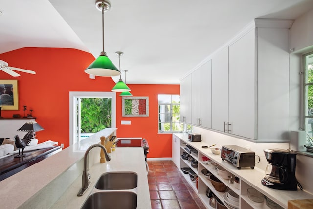 kitchen featuring light countertops, pendant lighting, white cabinetry, and a sink