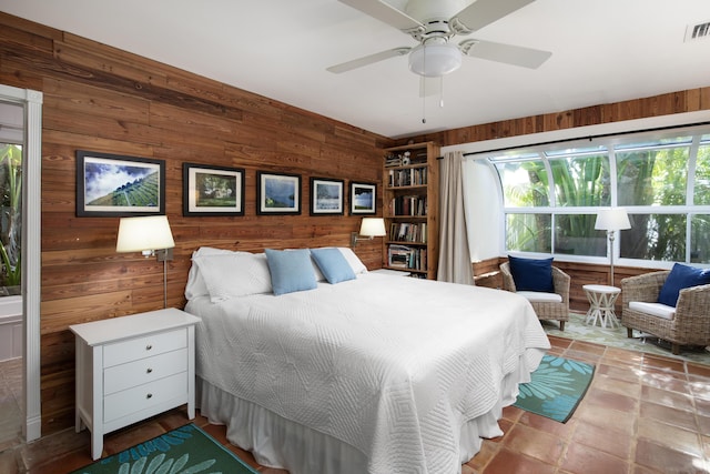 bedroom with visible vents, ceiling fan, and wooden walls