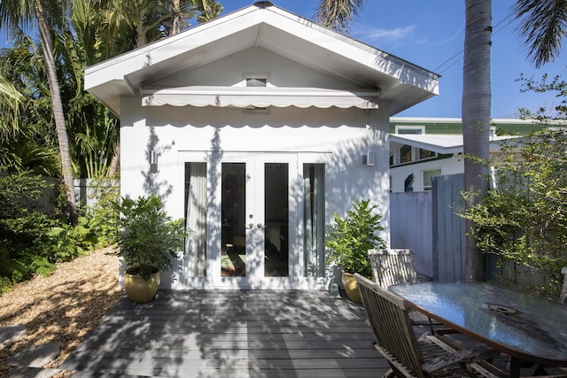 back of property with french doors, fence, a wooden deck, and stucco siding