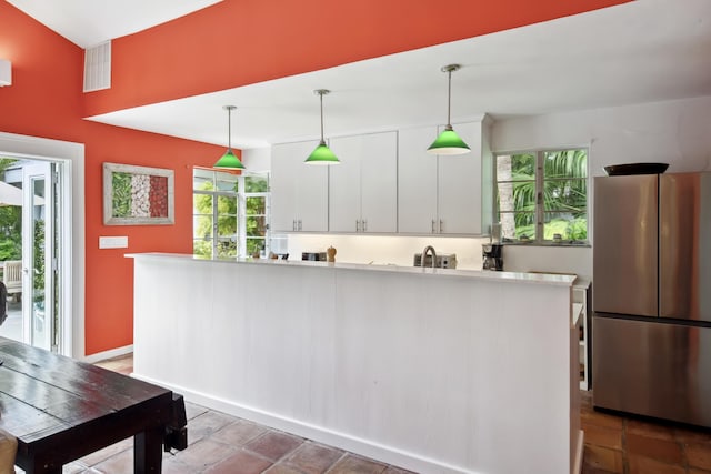 kitchen featuring pendant lighting, white cabinets, light countertops, and freestanding refrigerator