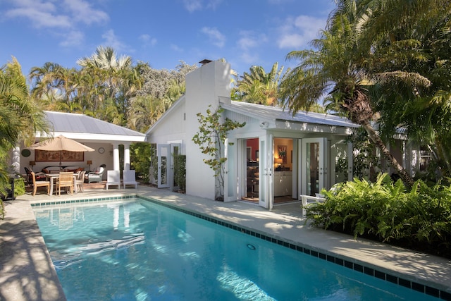 outdoor pool featuring a storage structure, an outdoor hangout area, a patio, and an outbuilding