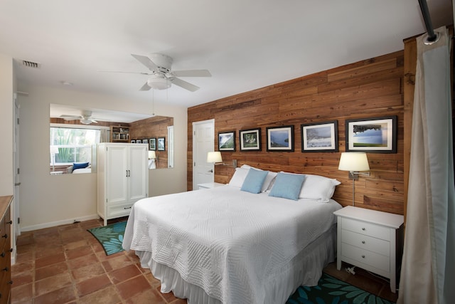 bedroom featuring stone finish flooring, wood walls, visible vents, and a ceiling fan