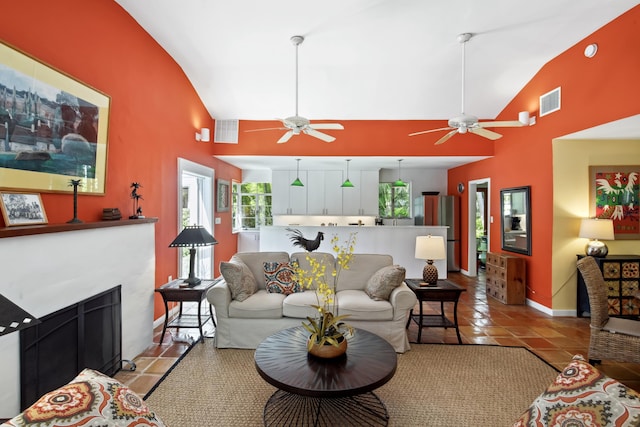 living area with light tile patterned floors, visible vents, high vaulted ceiling, and a tile fireplace