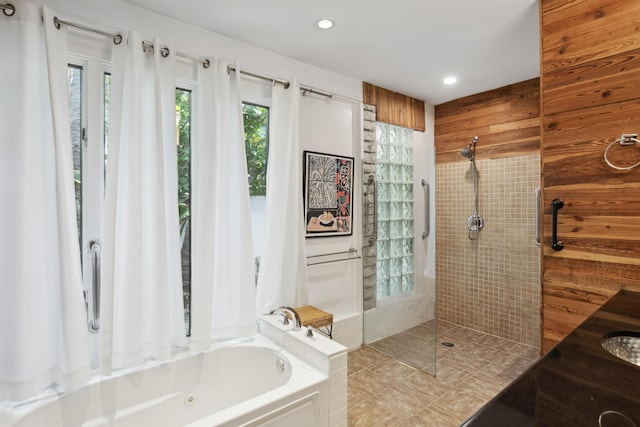 full bath with a walk in shower, recessed lighting, wooden walls, vanity, and a tub with jets