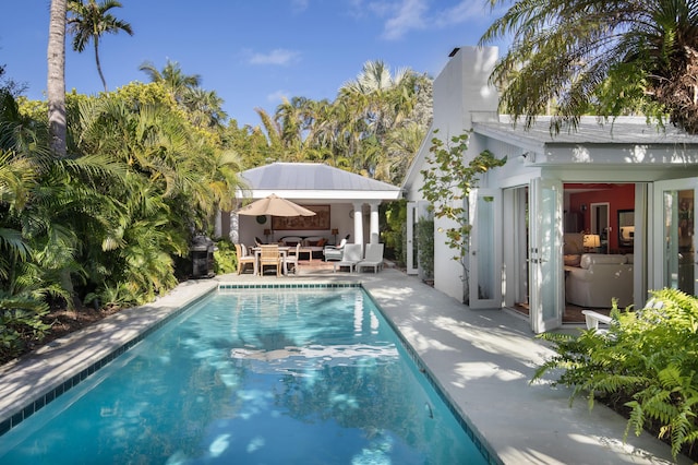 outdoor pool featuring an outbuilding, a patio area, an exterior structure, and an outdoor living space