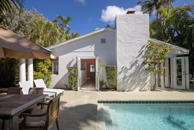 back of house featuring a patio, a chimney, stucco siding, and an outdoor pool