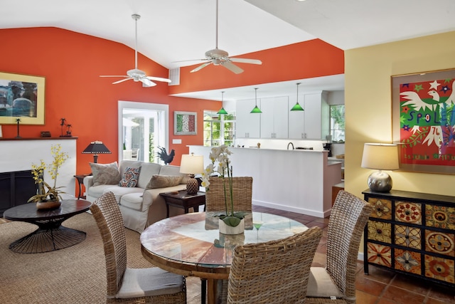 dining area featuring a fireplace, vaulted ceiling, and dark tile patterned flooring