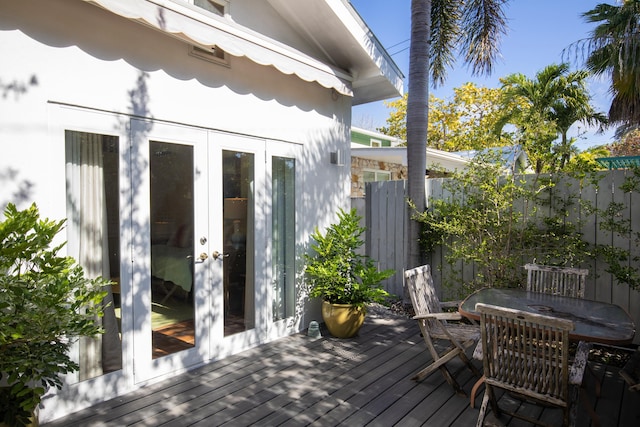 deck featuring french doors, outdoor dining space, and fence