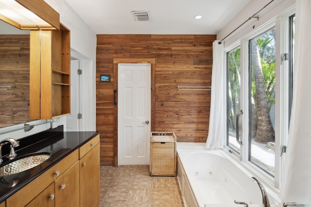 full bathroom featuring visible vents, wooden walls, a tub with jets, and vanity