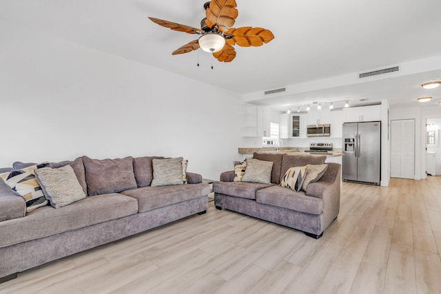 living room with ceiling fan, track lighting, and light hardwood / wood-style flooring