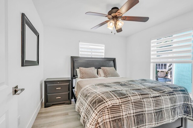 bedroom with multiple windows, ceiling fan, and light hardwood / wood-style floors