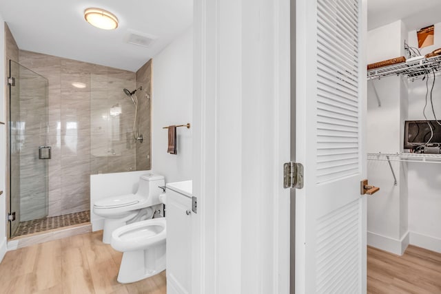 bathroom with a bidet, wood-type flooring, walk in shower, and toilet