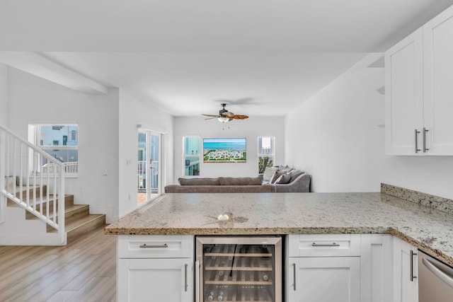 kitchen featuring white cabinetry, light stone countertops, and wine cooler