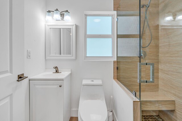 bathroom with tiled shower, vanity, and toilet