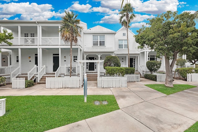 townhome / multi-family property with covered porch and a front lawn