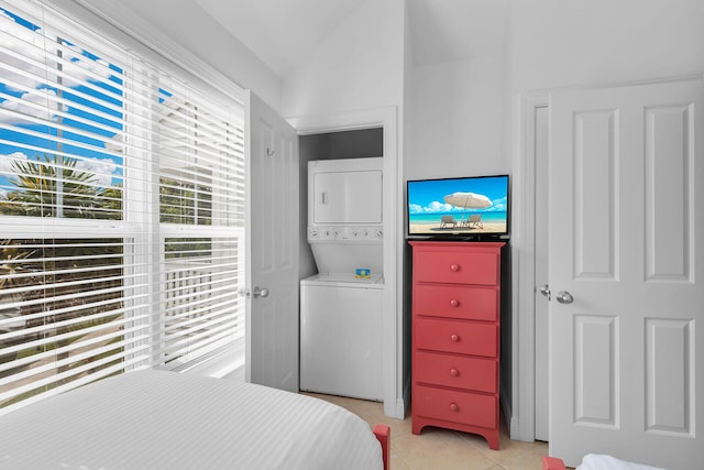 tiled bedroom with stacked washer / drying machine and vaulted ceiling