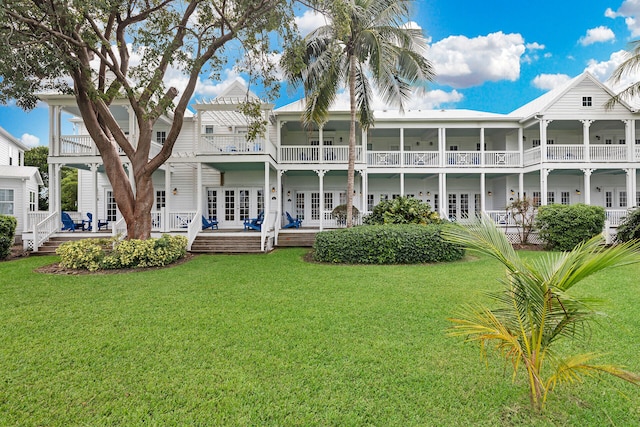 rear view of property with french doors, a balcony, and a lawn