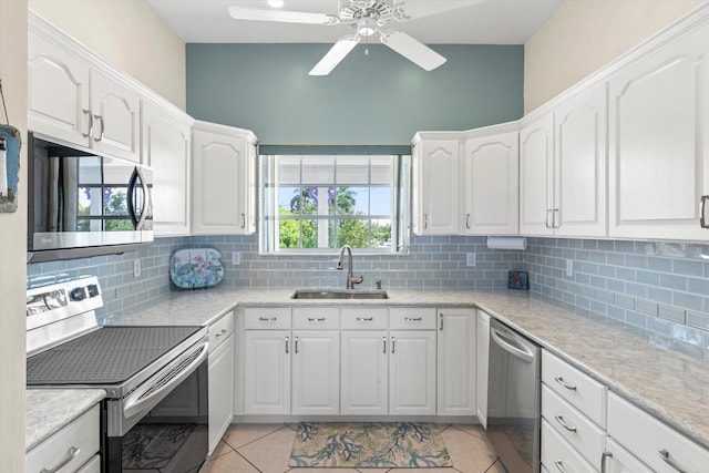 kitchen featuring sink, light tile patterned floors, appliances with stainless steel finishes, white cabinets, and decorative backsplash