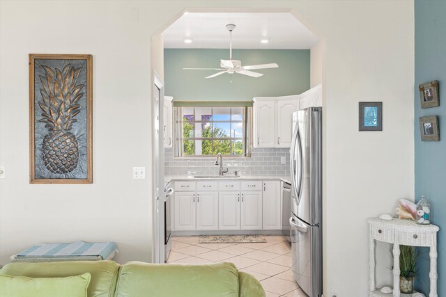 kitchen with sink, light tile patterned floors, stainless steel appliances, decorative backsplash, and white cabinets