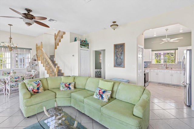 living room featuring ceiling fan with notable chandelier, sink, and light tile patterned floors