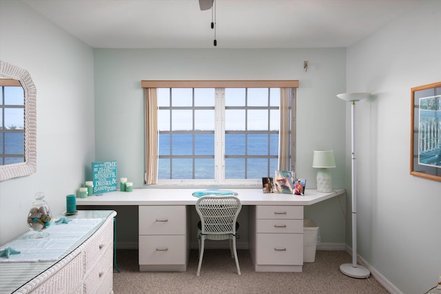 office space with a water view, light colored carpet, and built in desk