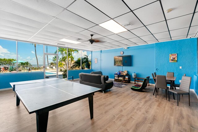 rec room featuring a drop ceiling, light hardwood / wood-style floors, and ceiling fan