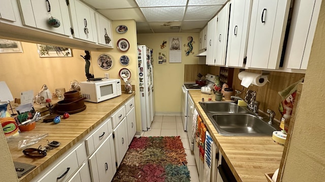 kitchen featuring white appliances, sink, a paneled ceiling, and white cabinets