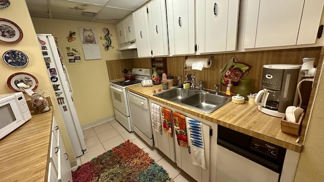 kitchen featuring a paneled ceiling, white cabinetry, sink, light tile patterned floors, and white appliances