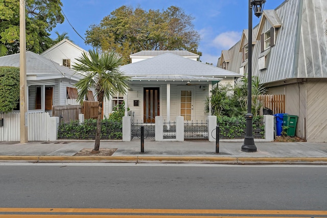 view of front of home with a porch, a standing seam roof, metal roof, and a fenced front yard