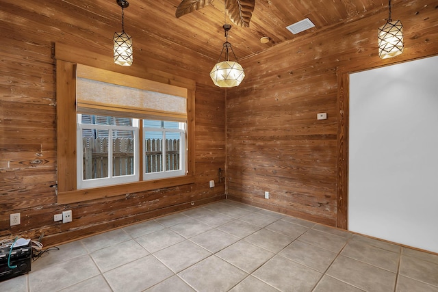 unfurnished room featuring wood walls, visible vents, and tile patterned floors