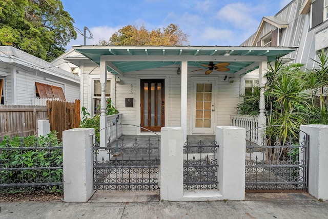 exterior space featuring a fenced front yard, covered porch, ceiling fan, and a gate