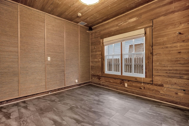 empty room featuring wooden ceiling and wood walls