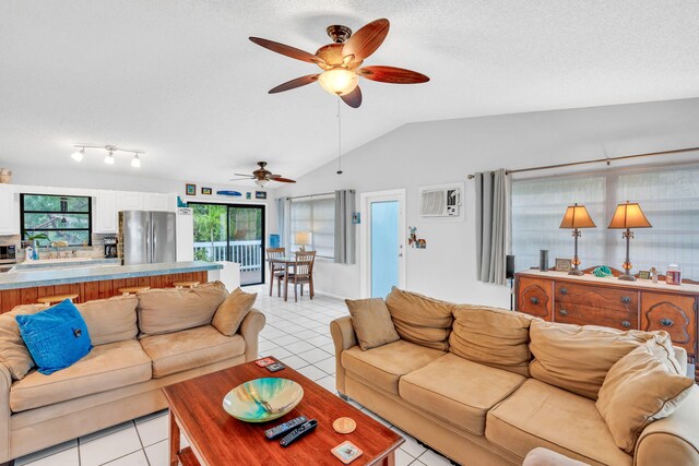 living room featuring vaulted ceiling, light tile patterned floors, ceiling fan, and a textured ceiling