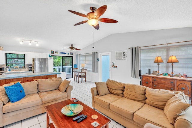 living room featuring vaulted ceiling, light tile patterned floors, ceiling fan, and a textured ceiling