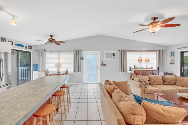 living room with lofted ceiling, light tile patterned floors, a textured ceiling, and a wall mounted AC