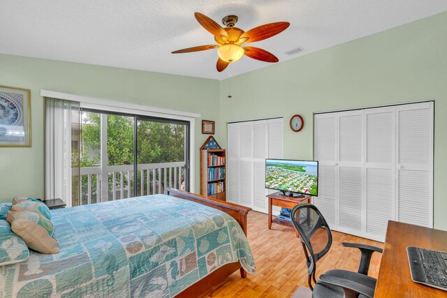 bedroom with hardwood / wood-style flooring, ceiling fan, vaulted ceiling, a textured ceiling, and access to outside