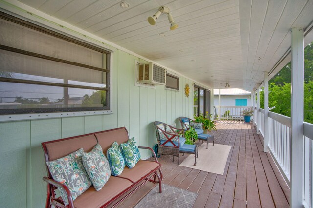 deck with an AC wall unit and covered porch