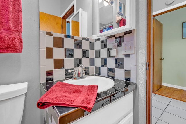 bathroom featuring toilet, vanity, tile patterned floors, and decorative backsplash