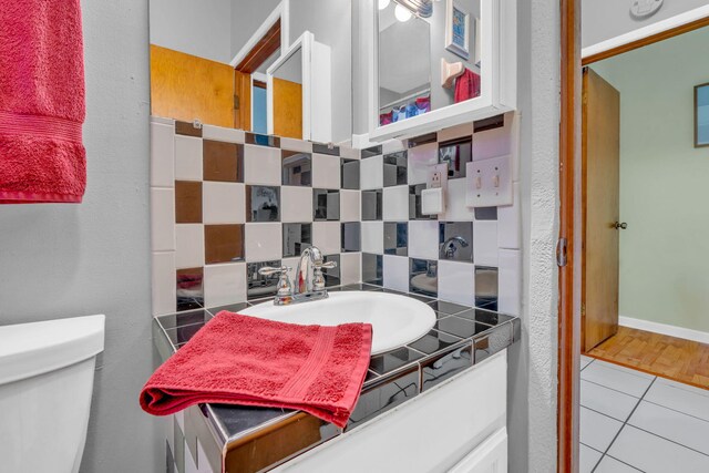 bathroom featuring toilet, vanity, tile patterned floors, and decorative backsplash