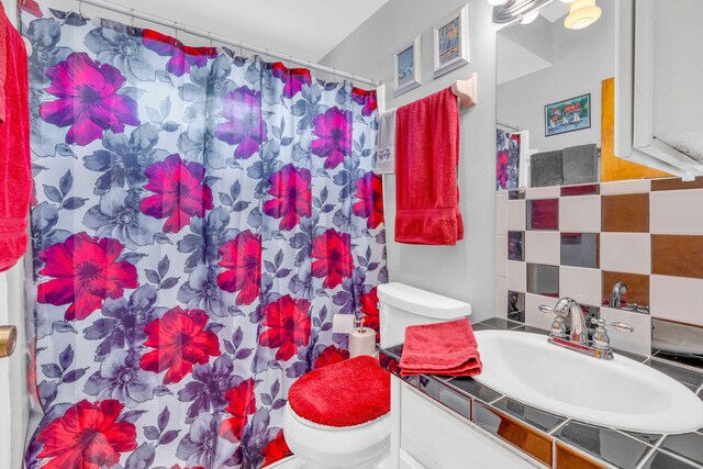 bathroom with vanity, toilet, and decorative backsplash