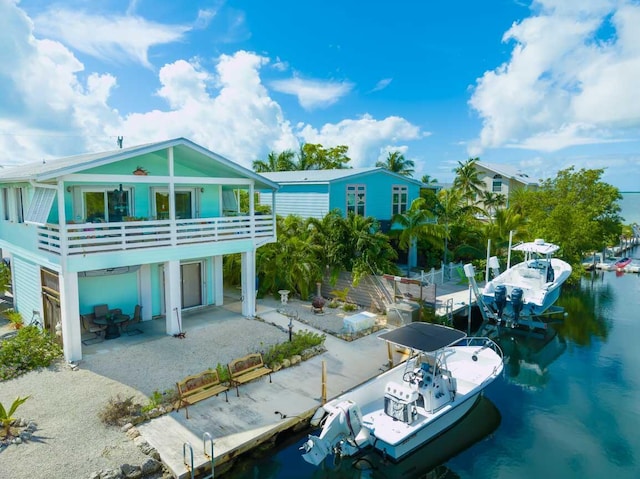 back of property with a patio and a water view