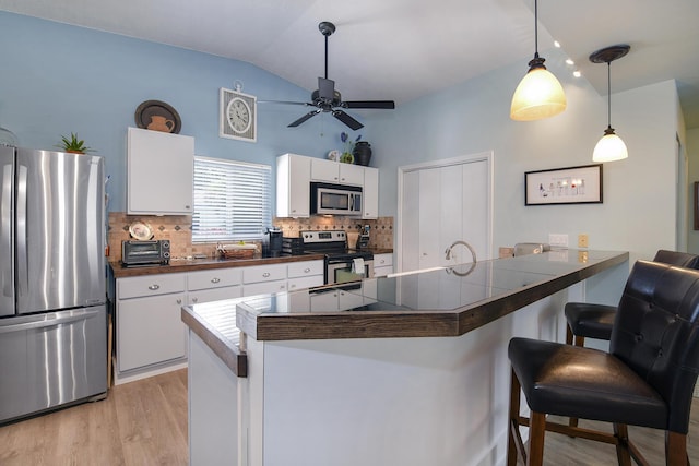 kitchen featuring white cabinetry, hanging light fixtures, a kitchen breakfast bar, kitchen peninsula, and stainless steel appliances