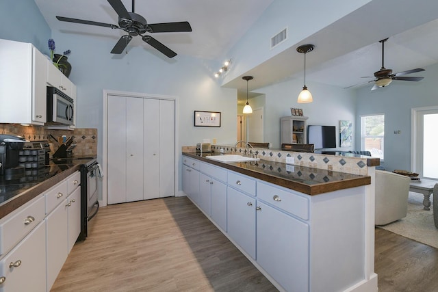 kitchen featuring electric stove, sink, white cabinetry, tasteful backsplash, and kitchen peninsula