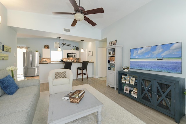 living room with ceiling fan, lofted ceiling, and light wood-type flooring