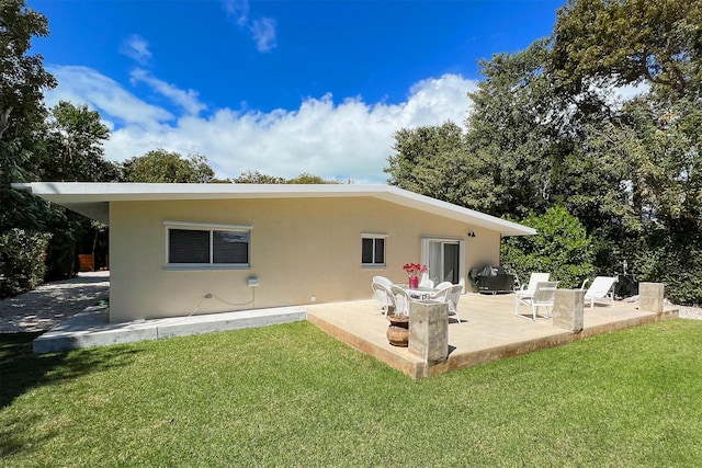 back of house with a patio and a lawn